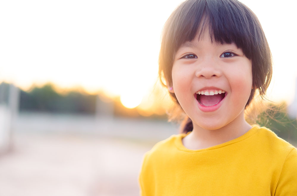 Happy Little asian girl child showing front teeth with big smile