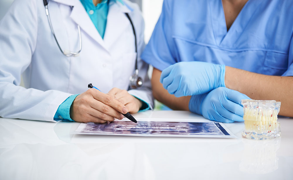 Portrait of female dentist and male surgeon examining teeth x-ra
